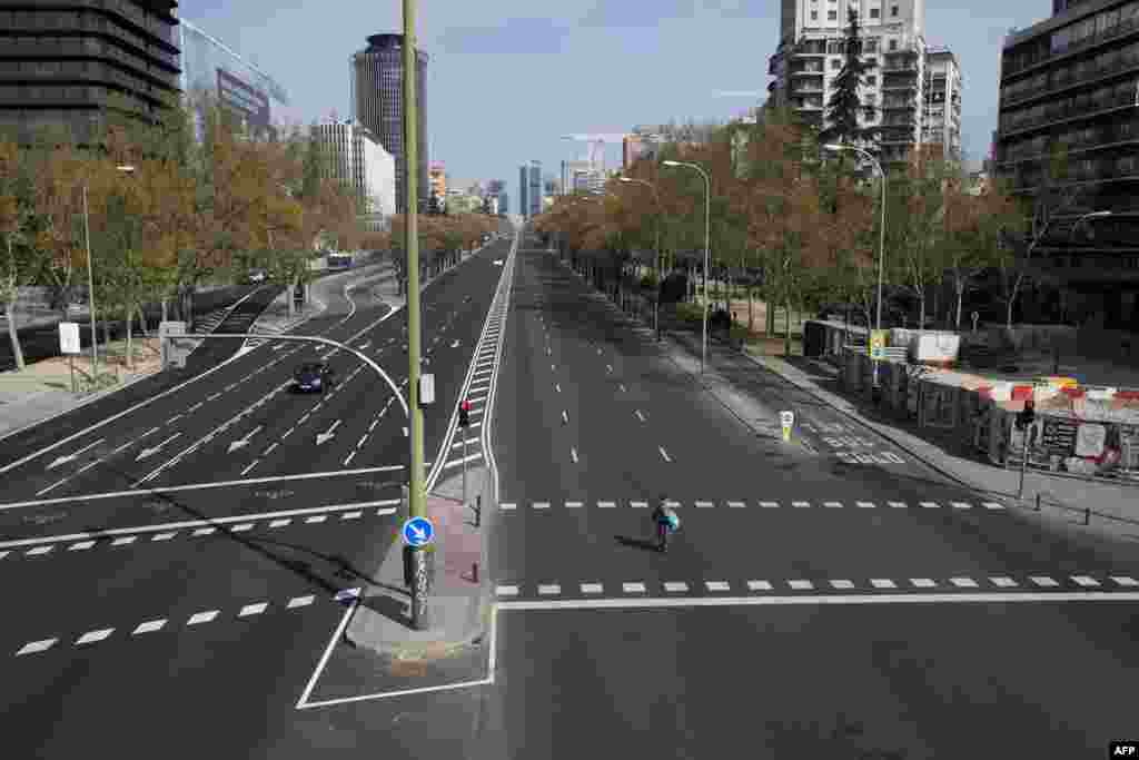 A woman crosses the usually busy La Castellana avenue in Madrid, Spain. France and Spain are the latest European nations to severely curtail people's movements to fight the coronavirus pandemic.