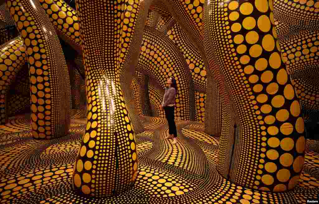 A visitor walks through a part of Japanese artist Yayoi Kusama's installation "You, Me and The Balloons" during a preview ahead of the start of the Manchester International Festival in Manchester, Britain.