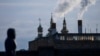 FILE - A woman walks with a power plant in the background, in Vinnytsia, Ukraine, March 16, 2022. Russia launched a cyberattack against a power plant near Kyiv in March 2023 and followed up with a missile strike shortly after the Ukrainian cyber response team arrived. 