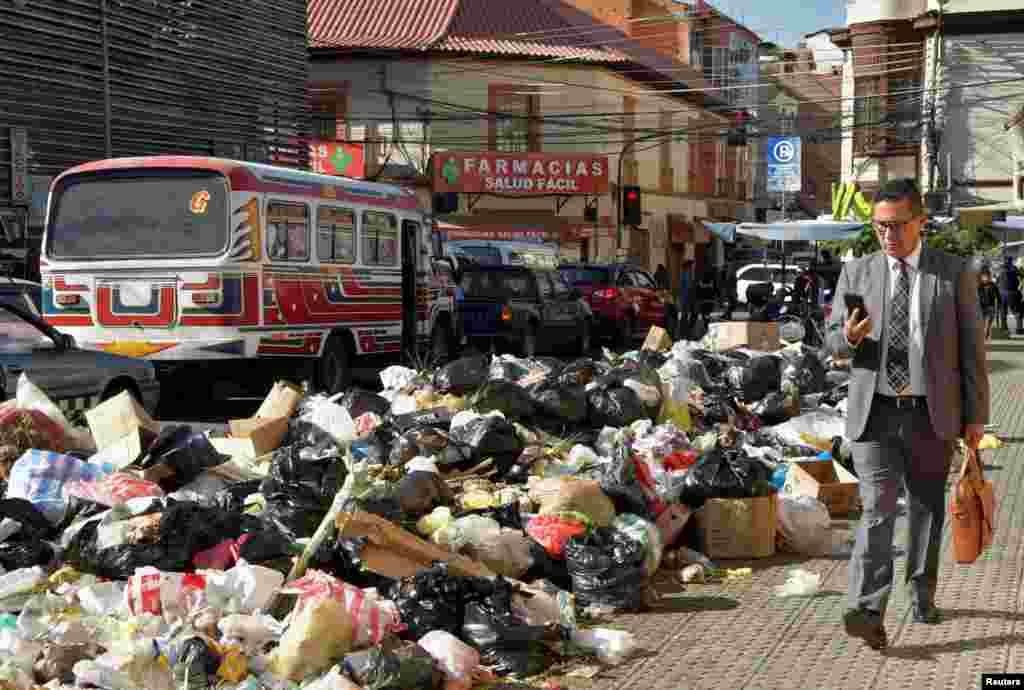 A man walks near garbage accumulated in the streets over several days since residents of the Tamborada neighborhood began blocking access to the K'ara K'ara landfill, because of a dispute over land prices with a local university, in Cochabamba, Bolivia, April 24, 2023.