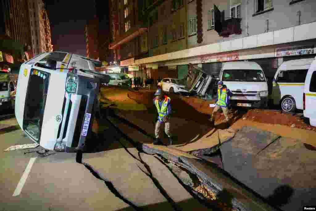 Police officers inspect damaged cars and the road after a suspected gas explosion injured people and caused significant damage, in the central business district of Johannesburg, South Africa, July 19, 2023.