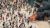 Protesters run toward riot police officers during a mass rally called by the opposition leader Raila Odinga over the high cost of living in Kibera Slums, Nairobi, March 27, 2023.