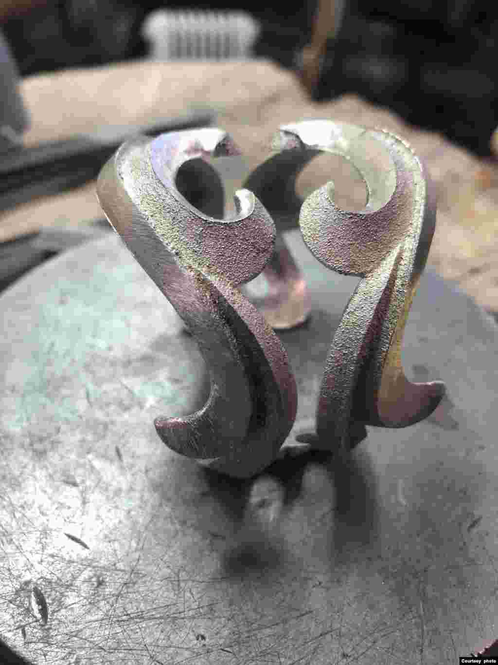 The artist bends the bracelet to shape.