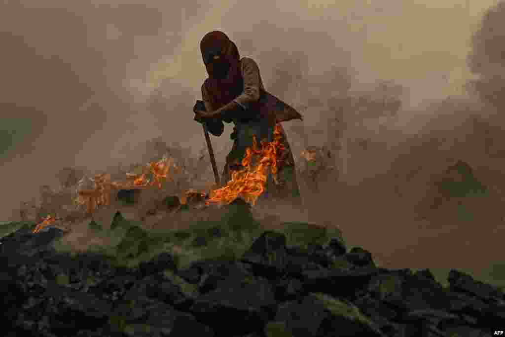 A girl burns raw coal near an open cast mining site on the outskirts of Dhanbad, India.