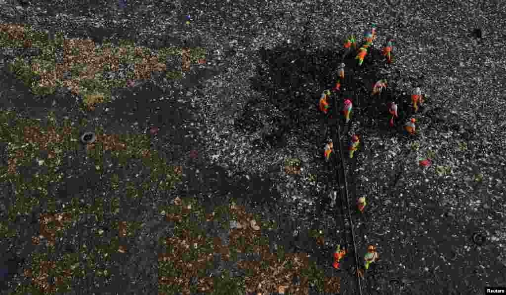 An aerial view show municipality workers collecting garbage, most of which is plastic and domestic waste, during World Oceans Day along the shore of Jakarta, Indonesia.