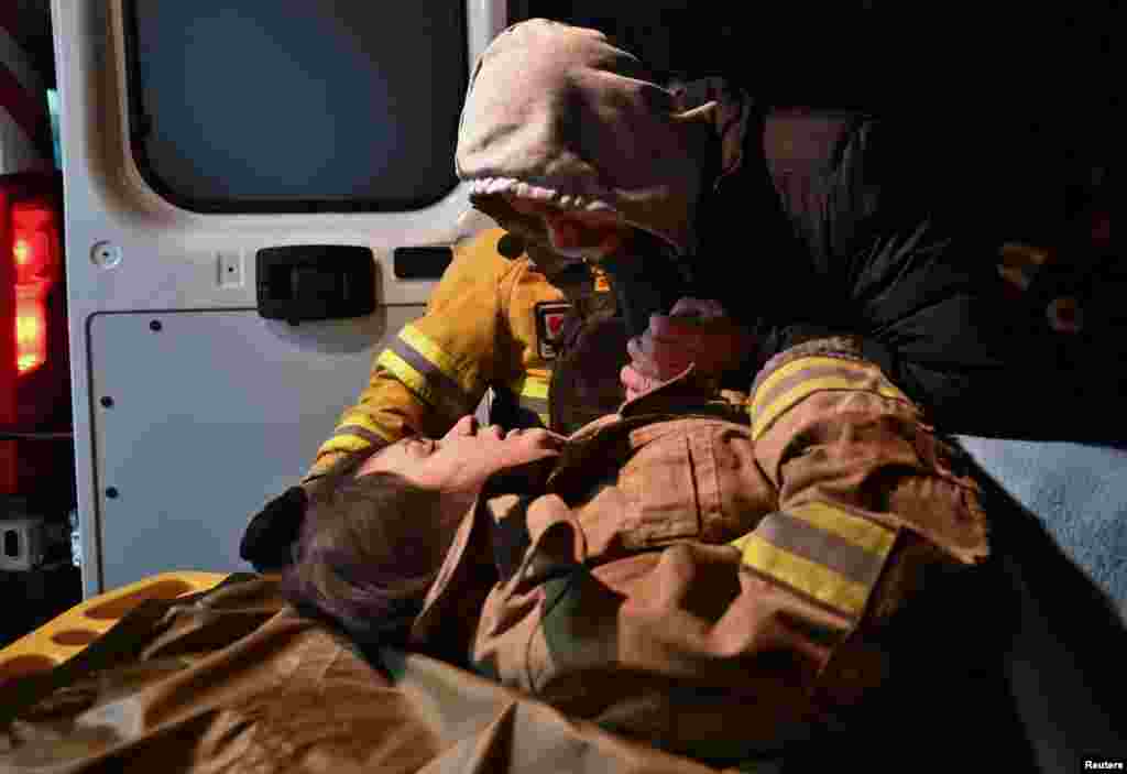 Local resident Yurii holds the hand of his pregnant relative Anna, 27, after she was rescued from a residential building heavily damaged by a Russian missile strike in Zaporizhzhia, Ukraine.