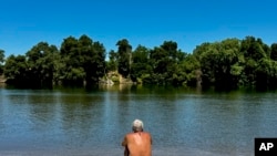 Un hombre se refresca junto al río en Sacramento, California, el martes 2 de julio de 2024, algunas zonas de California experimentaron un fuerte calor el martes y solo se esperaba que las cosas empeoraran durante la semana festiva del 4 de julio en Estados Unidos.
