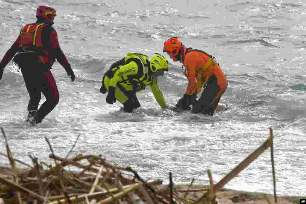 Rescuers recover a body after a migrant boat broke apart in rough seas, at a beach near Cutro, southern Italy. A wooden boat crowded with migrants smashed into rocky reefs and broke apart before dawn off the Italian coast. Rescuers had recovered nearly 60 bodies, and dozens more people were missing in the turbulent water. 