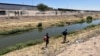 En Ciudad Juárez, México, una mujer camina con su hijo por el borde del Río Bravo buscando entregarse a las autoridades el 11 de mayo de 2023.