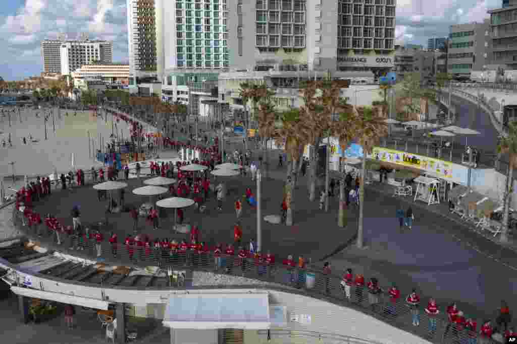 Israeli women's rights activists form a human chain along the beach to mark International Women's Day and protest against plans by Prime Minister Benjamin Netanyahu's new government to overhaul the judicial system, in Tel Aviv.