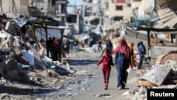 Palestinians walk past the ruins of houses destroyed during Israel's military offensive, amid the ongoing conflict between Israel and Hamas, in Gaza City, March 20, 2024.