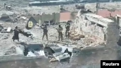 A still image taken from video released March 2, 2023, by founder of Russia's Wagner Group Yevgeny Prigozhin's press service, shows what it said to be Wagner fighters standing with a flag on top of a building in Bakhmut, Ukraine. (Press service of Concord/Handout via Reuters)
