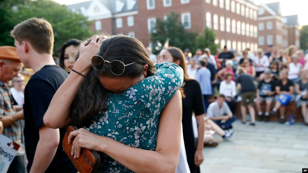 FILE - People hug as they gather for a vigil in response to a fatal shooting in the Capital Gazette newsroom, June 29, 2018, in Annapolis, Maryland. Journalists, who report on tragedy daily, experience trauma at rates comparable to first responders, according to a recent study. 