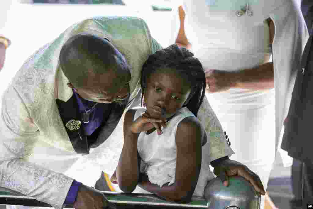 Eddie Owens talks with his daughter, Africa, at the gravesite after the funeral for Africa's mother, Ajike Owens, at Highland Memorial Park in Ocala, Florida, June 12, 2023. Owens was fatally shot by her neighbor Susan Lorincz when she went to Lorincz's door. Lorincz was arrested and charged in the shooting.