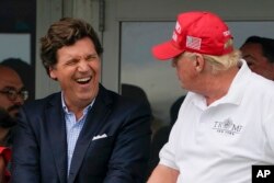 FILE - Tucker Carlson, left, and former President Donald Trump, right, react during the final round of the Bedminster Invitational LIV Golf tournament in Bedminster, N.J., July 31, 2022.