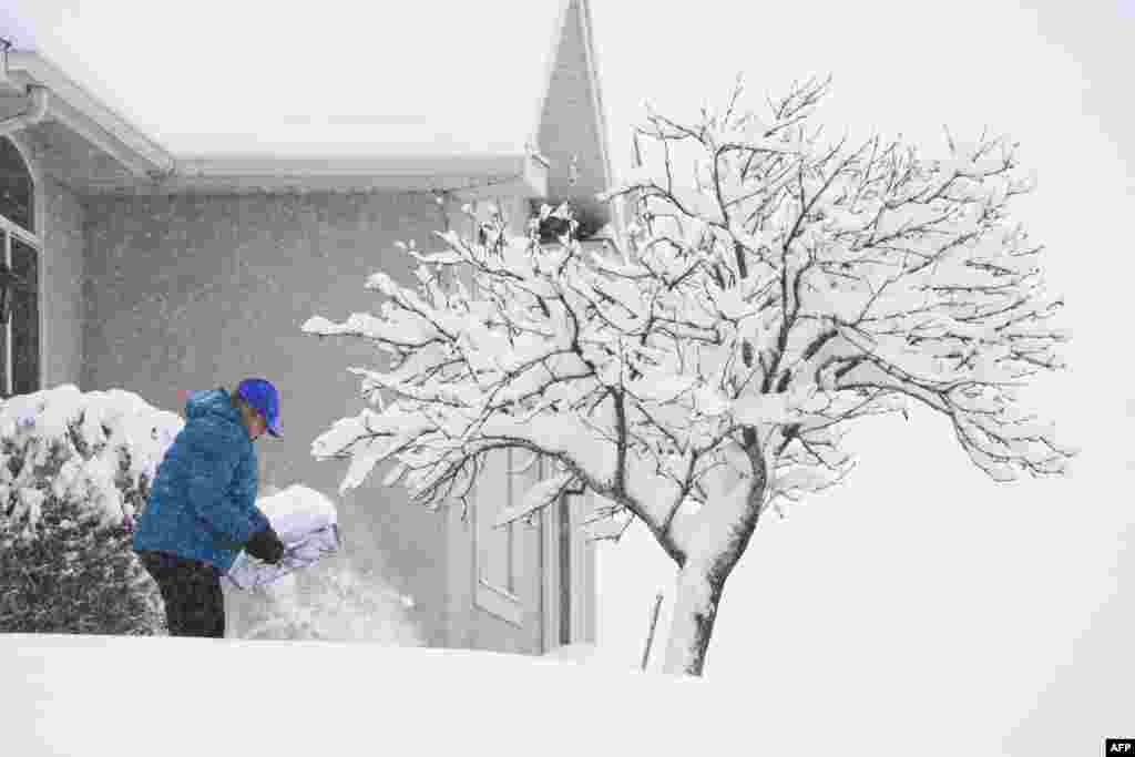 A person shovels their sidewalk in Provo, Utah, Feb. 22, 2023. Powerful winter storms lashed the United States, with heavy snow snarling travel across wide areas, even as unusual warmth was expected in others.