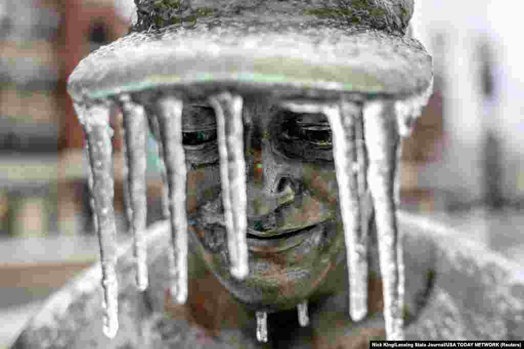 Icicles hang from the hat of a figure that is part of the Hometown Hero baseball sculpture outside Jackson Field in Lansing, Michigan.