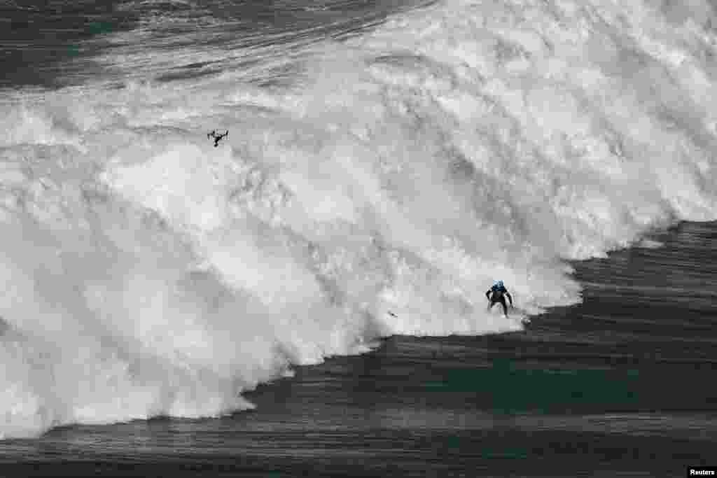 A surfer rides a wave in Praia do Norte, Nazare, Portugal.