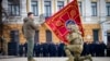 El presidente de Ucrania, Volodymyr Zelenskyy, sostiene la bandera de una unidad militar mientras un oficial la besa durante un evento conmemorativo con motivo del primer aniversario de la guerra entre Rusia y Ucrania en Kiev, Ucrania, el 24 de febrero de 2023.