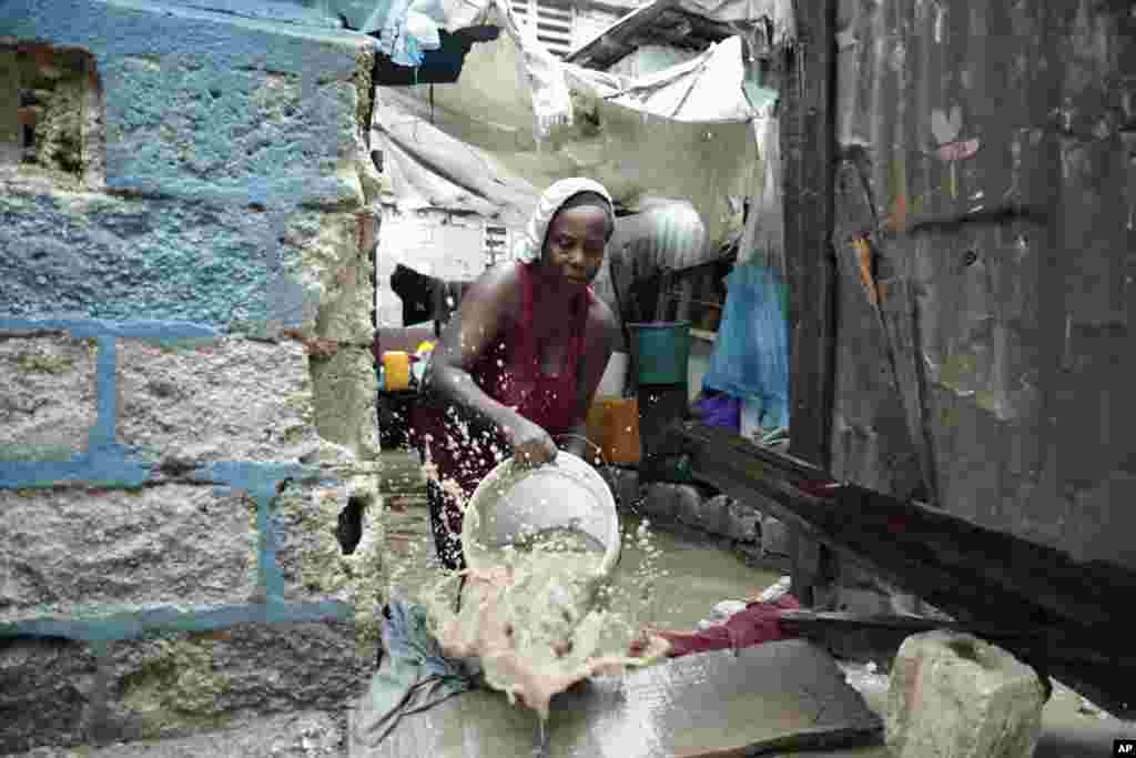 A woman uses a bucket to remove water from inside her flooded house, after a heavy rain in Port-au-Prince, Haiti, June 3, 2023.