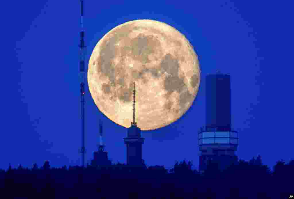 The moon sets behind buildings on top of the Feldberg mountain near Frankfurt, Germany.