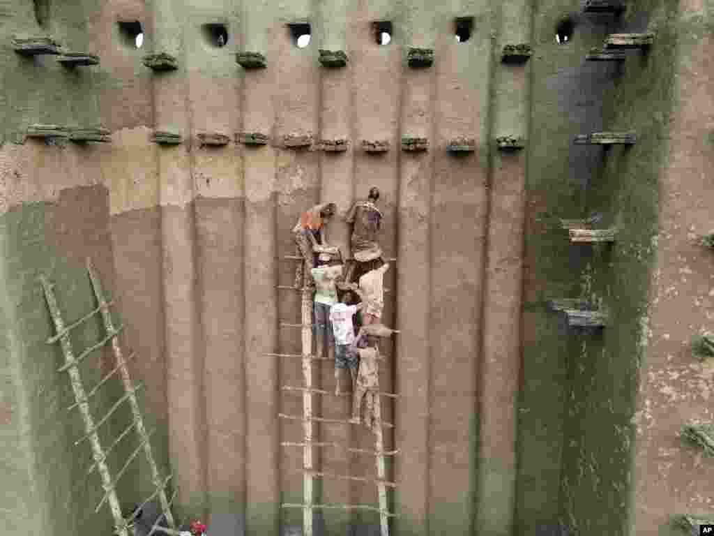 Malians take part in the annual replastering of the world's largest mud-brick building, the Great Mosque of Djenne, Mali, May 12, 2024.