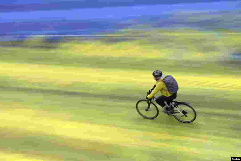 A cyclist rides on a painted road, after Protest group 'Led by Donkeys' spread paint in the colors of the Ukrainian flag on the road, outside the Russian Embassy in London, ahead of the first anniversary of Russia's invasion of Ukraine.