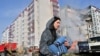 A woman walks past damaged residential buildings as she carries a child in Uman, around 215 km south of Kyiv, on April 28, 2023, after Russian missile strikes targeted several Ukrainian cities overnight. (Photo by Sergei SUPINSKY/ AFP)
