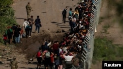 Migrantes que buscan asilo, en su mayoría de Venezuela y Cuba, son detenidos por agentes de Aduanas y Protección Fronteriza de Estados Unidos después de cruzar el río Bravo hacia EEUU desde México en Eagle Pass, Texas, el 13 de julio de 2022.