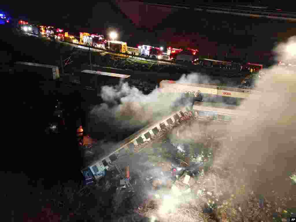Smoke rises from trains as firefighters and rescuers operate after a collision near Larissa city, Greece. A passenger train and a freight train collided head-on in central Greece just before midnight Tuesday, killing at least 38 people and injured scores. 