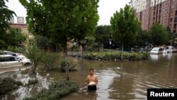 資料照：河北涿州一名男子手拿食物走在積滿洪水的街道上。 （2023年8月3日）