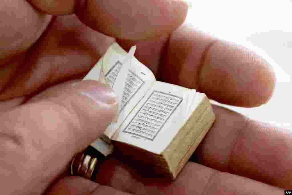Mario Prushi holds one of the smallest Quran of a postage-stamp size with a cover crafted from gold embroidered velvet, in his hand, in Tirana, Albania.