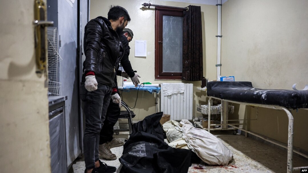 Men stand over the bodies of two victims who were killed in the aftermath of reported bombardment by Syrian government forces, at a hospital in the rebel-held city of Idlib in northwestern Syria, Dec. 30, 2023. 