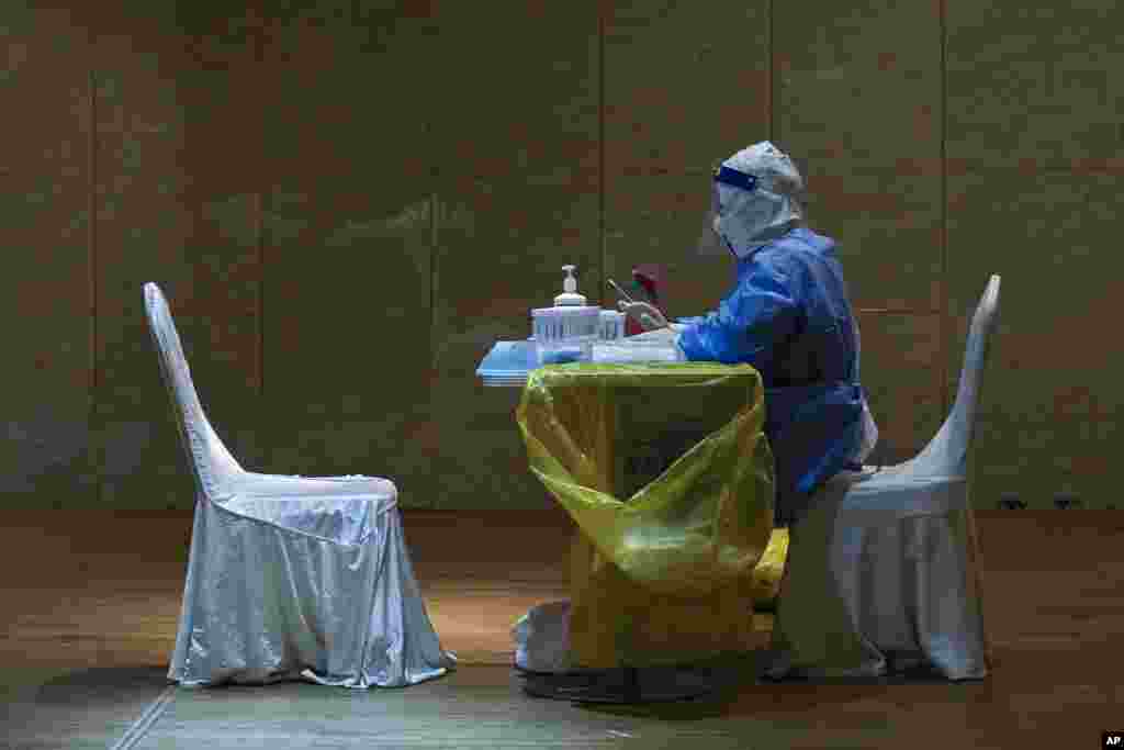 A medical worker in protective gear waits to administer COVID-19 tests for reporters who signed up to cover the press conference and the opening of the Chinese People's Political Consultative Conference at a quarantine hotel in Beijing.