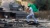 A Palestinian youth holds a Hamas flag during confrontations with Israeli troops at the northern entrance of Ramallah, West Bank, near the Israeli settlement of Beit El, Oct. 27, 2023, as battles continue between Israel and Hamas.