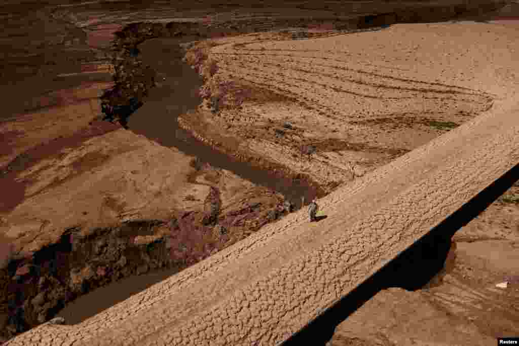 A man walks on the cracked ground of the Baells reservoir, as drinking water supplies plunged to their lowest level because of extreme drought in Catalonia, in the village of Cersc, in the Bergueda region of Spain.