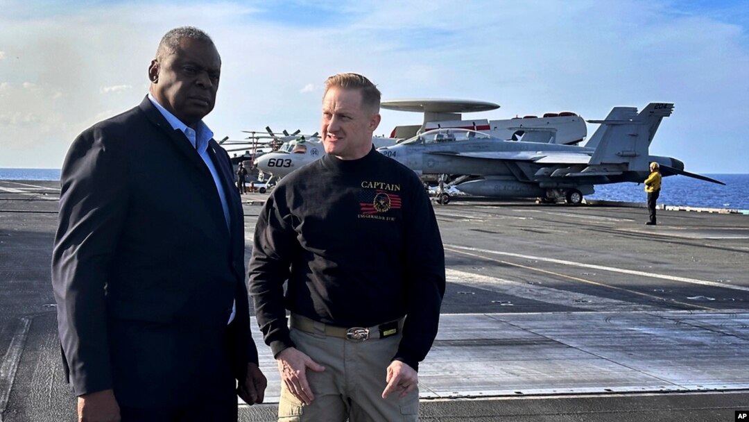 FILE - Defense Secretary Lloyd Austin, left, talks with the commanding officer of the USS Gerald R. Ford, Navy Capt. Rick Burgess, during an unannounced visit to the ship on Dec. 20, 2023.