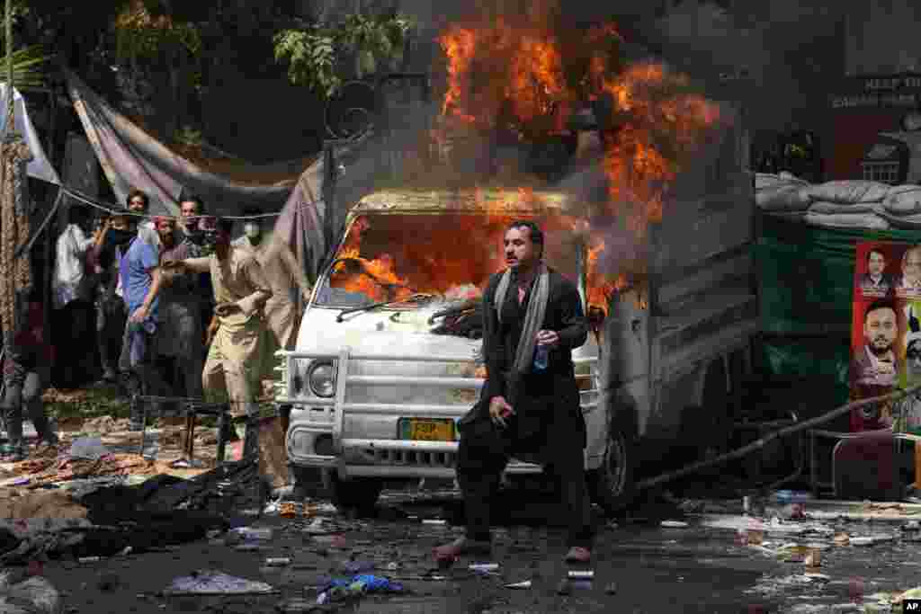 Supporters of former Prime Minister Imran Khan throw stones toward police as they stand next to a burning vehicle during clashes, in Lahore, Pakistan.