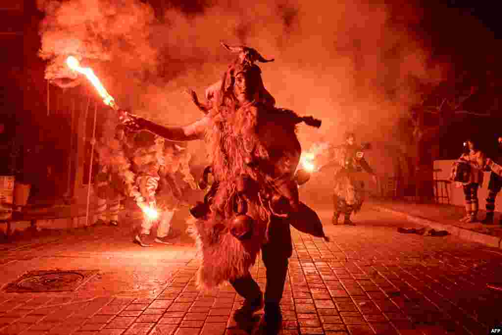 A reveler lights a flare during a procession marking a traditional carnival celebration in the city of Amfissa, central Greece, Feb. 25, 2023.