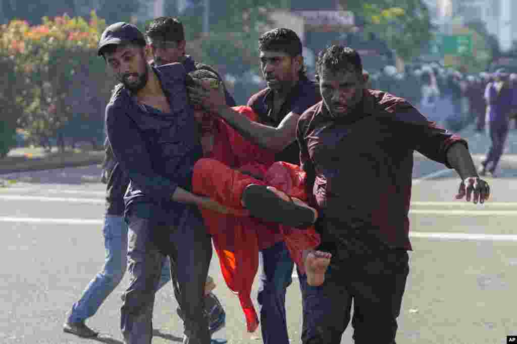 Members of Sri Lankan opposition political party National People's Power carry an injured Buddhist monk during a clash with police in Colombo. The opposition supporters were protesting over a decision to postpone local elections after the government said it cannot finance them because of the country's crippling economic crisis.