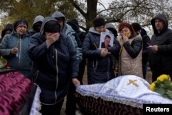 Rođaci nad kovčezima Irine Karbake i Oleksandra Kodaka, koji su bili među 59 civila ubijenih u ruskom raketnom napadu, u Hrozi u Ukrajini, 9. oktobra 2023.