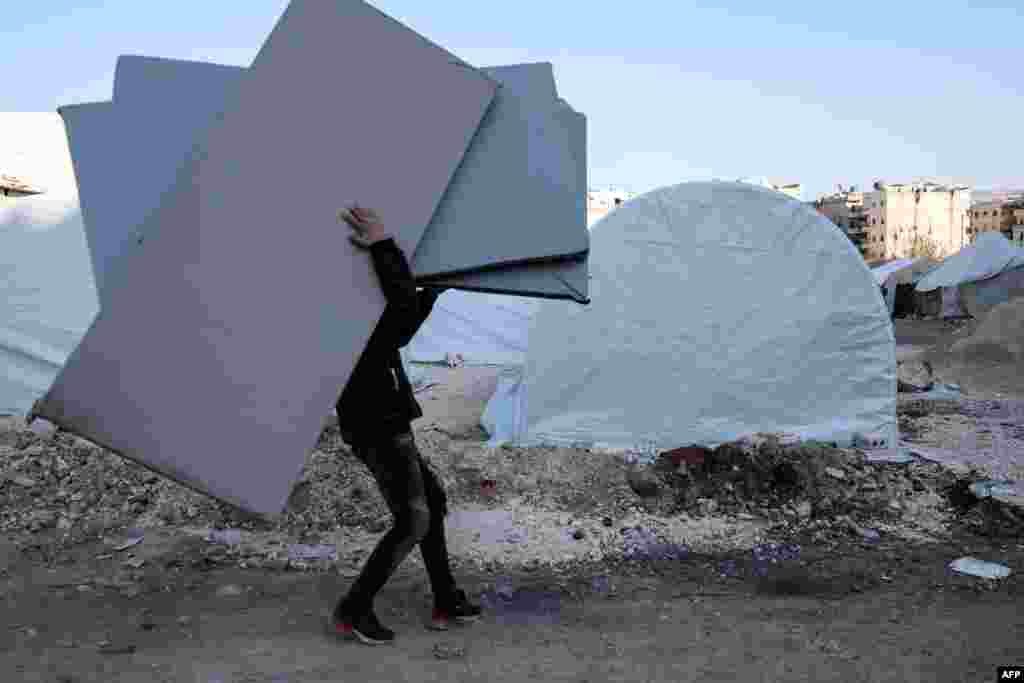 People receive mattresses distributed by an NGO, at a makeshift camp in the city of Afrin in the rebel-held part of Aleppo province, Syria, following the magnitude 7.8 earthquake that hit Turkey and Syria on Feb. 6.