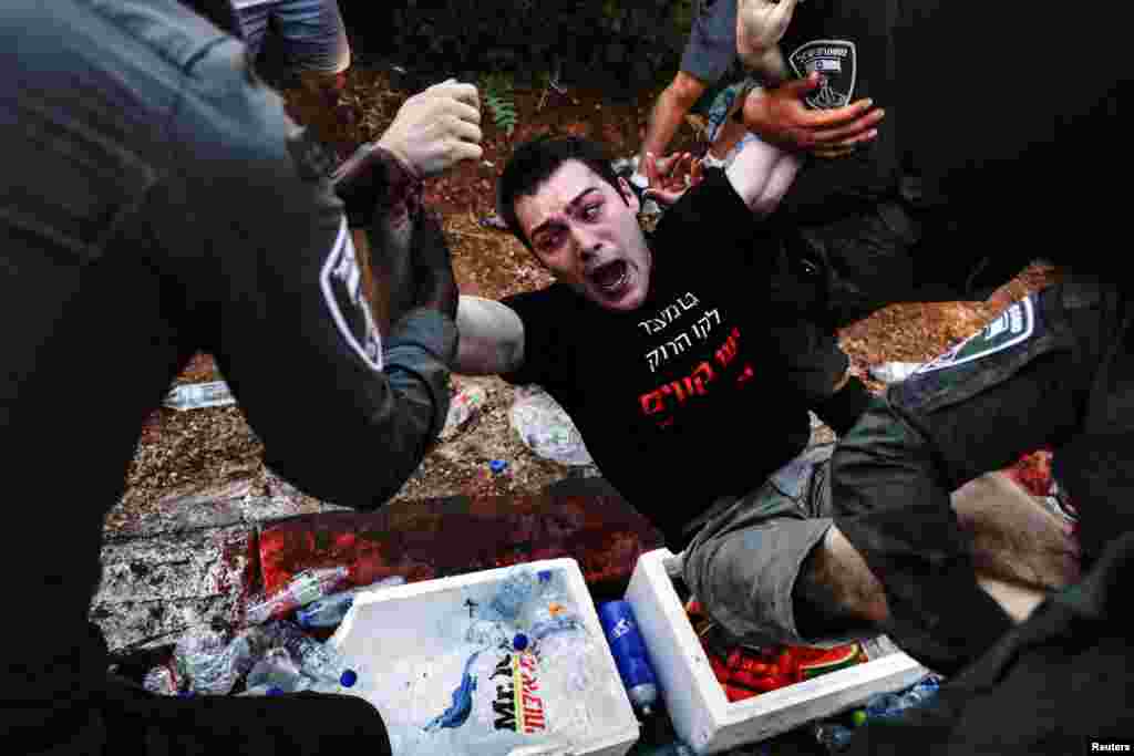 Israeli security forces clash with a protester during a demonstration against Israeli Prime Minister Benjamin Netanyahu and his nationalist coalition government's judicial overhaul, in Jerusalem.