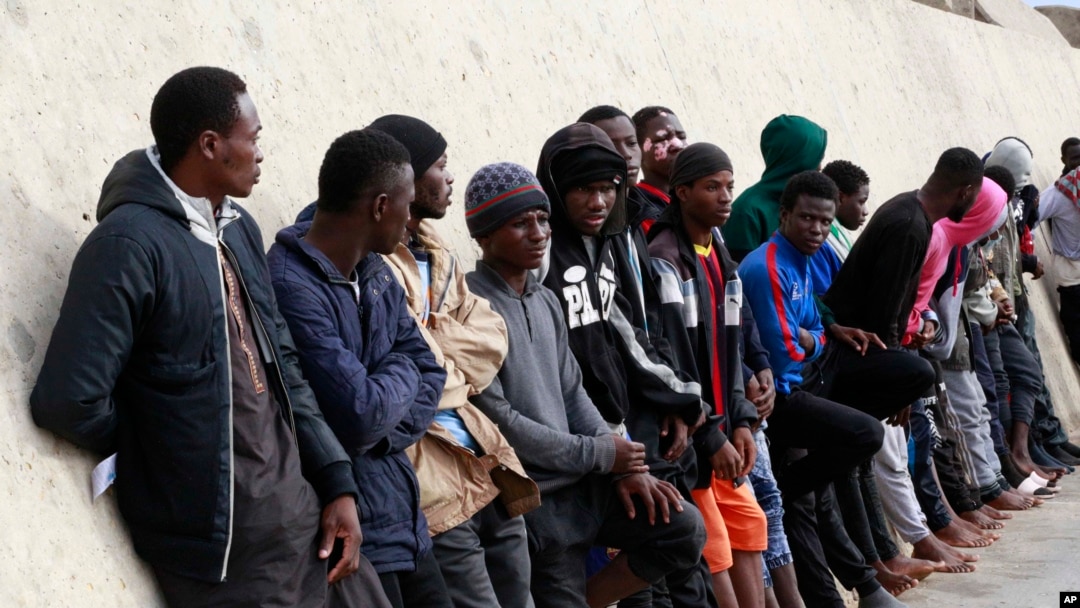 FILE - Migrants stand after being brought to shore by a Libyan coast guard at the Mediterranean Sea, in Garaboli Libya, Oct. 18, 2021.