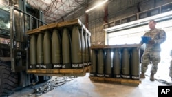 U.S. Air Force Staff Sgt. Cody Brown, right, with the 436th Aerial Port Squadron, checks pallets of 155 mm shells ultimately bound for Ukraine, April 29, 2022, at Dover Air Force Base, Delaware. (Alex Brandon/AP)