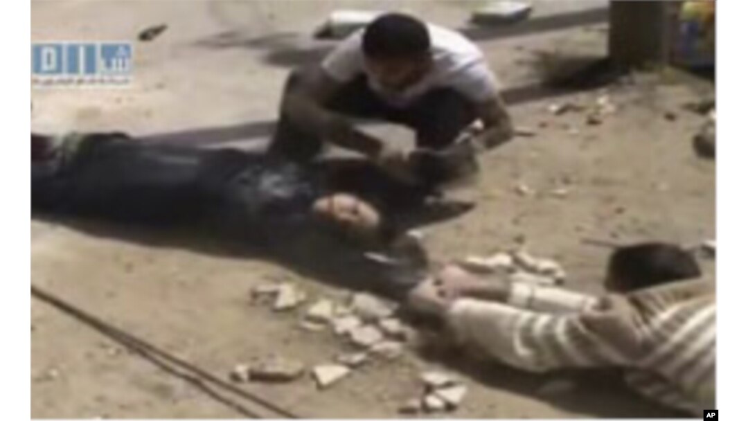 This amateur video image shot on April 24, 2011 and made available by SHAAM News Network and posted on Youtube, May 12, 2011, shows two men crawling close to the ground and dragging a woman to safety in Daraa, Syria