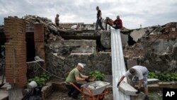 Volunteers clear rubble on the ground floor of Zhanna Dynaeva's and Serhiy Dynaev's house which was destroyed by Russian bombardment, in the village of Novoselivka, near Chernihiv, Ukraine, Aug. 13, 2022.