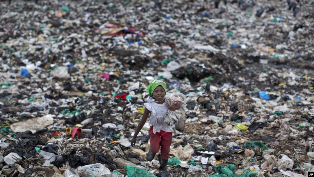 FILE - Joyce Njeri, 8, walks with a torn sack carrying the plastic bottles she has scavenged, at the garbage dump in the Dandora slum of Nairobi, Kenya.