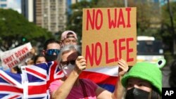FILE - A group of demonstrators wave signs at the Hawaii state Capitol during a rally over water contamination by the U.S. Navy near Pearl Harbor, in Honolulu, Feb. 11, 2022.