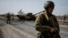 A Ukrainian serviceman stands near the wreck of a Russian tank on the front line in the Kyiv region, Ukraine, March 28, 2022. 